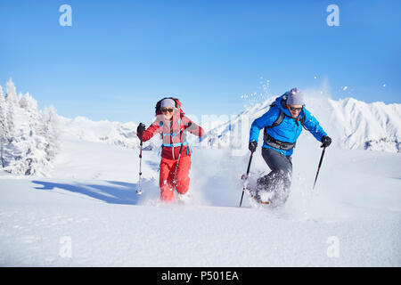 Austria, Tirolo, escursionisti con racchette da neve in esecuzione attraverso la neve Foto Stock