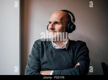 Senior uomo che indossa le cuffie e ascoltare della musica, ritratto Foto Stock