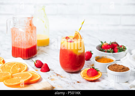 La fragola e orange smoothie con curcuma e cannella su marmo Foto Stock