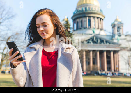 La Russia, San Pietroburgo, giovane donna utilizza lo smartphone nella città Foto Stock