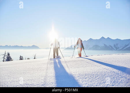 Austria, Tirolo, escursionisti con racchette da neve a sunrise Foto Stock