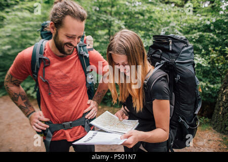 Felice coppia giovane su un viaggio escursionistico mappa di lettura Foto Stock