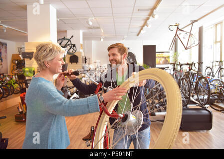 Addetto alle vendite ad aiutare il cliente nel negozio di biciclette Foto Stock