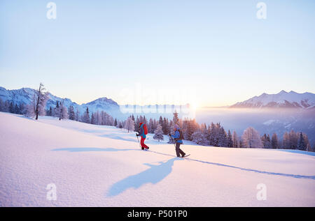 Austria, Tirolo, escursionisti con racchette da neve a sunrise Foto Stock