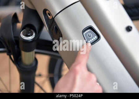 Puntare il dito sul commutatore di un e-bike Foto Stock