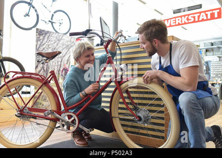 Addetto alle vendite ad aiutare il cliente nel negozio di biciclette Foto Stock