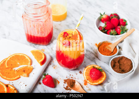 La fragola e orange smoothie con curcuma e cannella su marmo Foto Stock