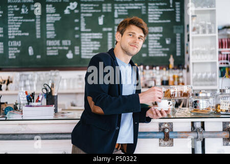 Ritratto di uomo sorridente con la tazza di caffè in un bar Foto Stock