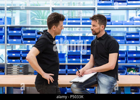 Conversazione tra due uomini in fabbrica e magazzino Foto Stock