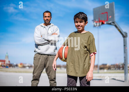 Ritratto di ragazzo con padre sul campo da basket all'aperto Foto Stock
