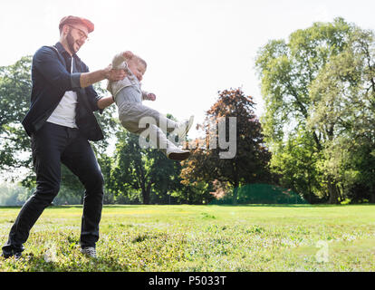 Padre Felice sollevando il figlio in un parco Foto Stock