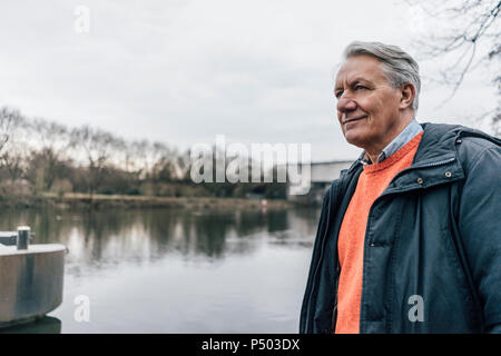 Uomo senior presso il riverside guardando lateralmente Foto Stock