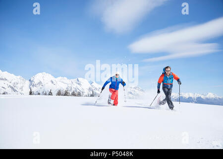 Austria, Tirolo, escursionisti con racchette da neve in esecuzione attraverso la neve Foto Stock