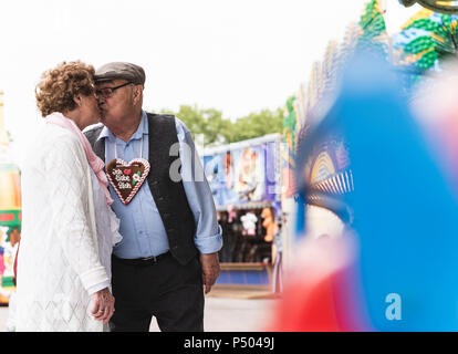 Coppia senior con pan di zenzero cuore baciare sulla fiera Foto Stock