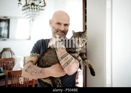 Tatuato uomo che porta il suo gatto Foto Stock