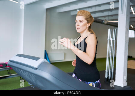 Donna in corsa sul tapis roulant in palestra Foto Stock