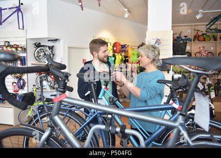 Addetto alle vendite ad aiutare il cliente nel negozio di biciclette Foto Stock