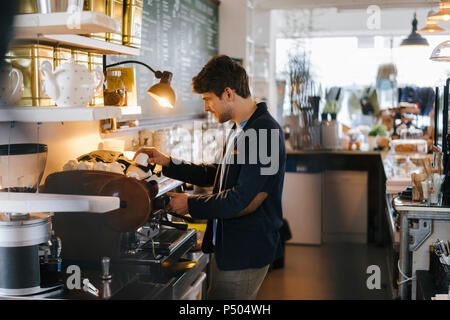 Uomo in una caffetteria tazze di smistamento Foto Stock