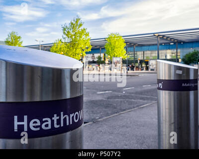 AEROPORTO DI HEATHROW, LONDRA - 17 MAGGIO 2018: I Bollards di sicurezza all'esterno dell'edificio del Terminal 3 con edificio del terminal sfocato sullo sfondo Foto Stock