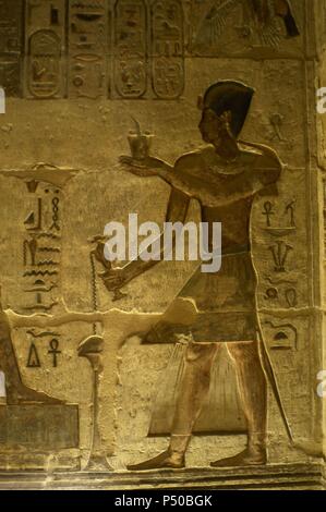 Tempio tolemaico di Hathor e Maat. Rilievi policromi che decorano l'interno. Il faraone facendo offerte e libagioni. Deir el-Medina. L'Egitto. Foto Stock