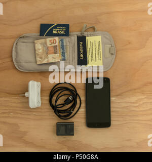 Travelig in Brasile: essenziale per un viaggio di cui su una tavola di legno: due passaporti e certificato internazionale di vaccinazione, telefono cellulare, caricabatterie, ada Foto Stock