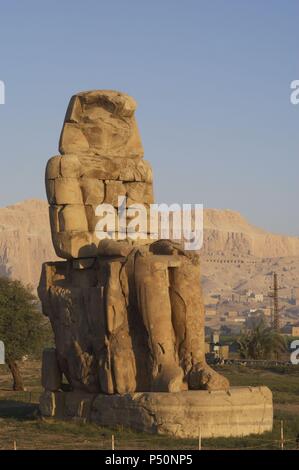 Colosso di Memnon. Statue in pietra raffigurante il faraone Amenhotep III (XIV secolo a.C.) in posizione seduta. Colosso orientale. Xviii dinastia. Nuovo Regno. Luxor. L'Egitto. Foto Stock