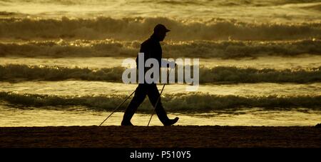 Silhouette di un uomo a piedi lungo la spiaggia. Spagna. Foto Stock