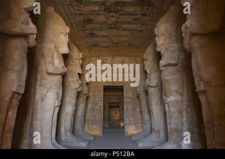Arte Egizia Grande Tempio di Ramses II (1290-1224 a.C.). Tempio funerario scavato nella roccia. Vista dall'interno della prima camera, con otto statue di Ramses II come il dio Osiride. Abu Simbel. L'Egitto. Foto Stock