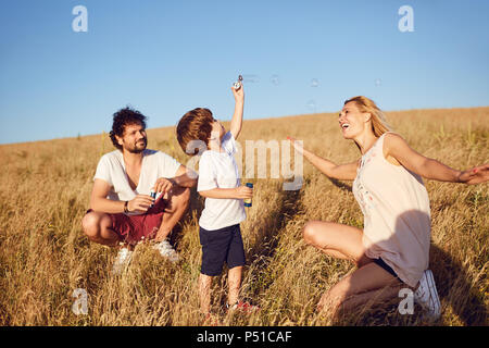 La famiglia è giocare con le bolle di sapone in natura Foto Stock