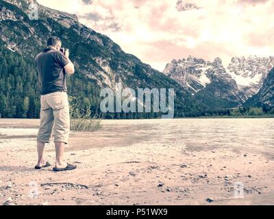 Photo Traveler sta prendendo foto di memoria del paesaggio lacustre. Lago Blu tra alte montagne, picchi toccare nel cielo blu. Viaggio il concetto di stile di vita Foto Stock