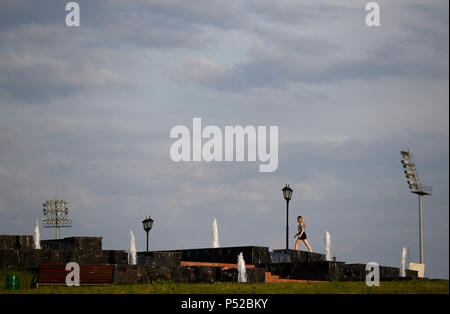 Saransk, Russia. Il 24 giugno 2018. Una giovane donna camminare passato proiettori in un parco. Credito: Andreas Gebert/dpa/Alamy Live News Foto Stock