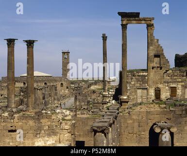 ARTE ROMANO. PROXIMO ORIENTE. BOSRA. Ruinas de la zona arqueológica romana de la ciudad. En primer término las columnas de la Fuente o ninfeo del S. II. Al fondo la Mezquita de Omar. SIRIA. Foto Stock