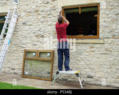 Finestra montatore di sostituire il vecchio con vetri doppi uPVC serramenti con nuovo solida quercia triplo vetro telai di finestra Foto Stock