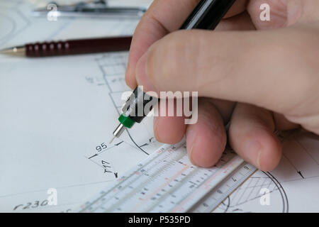 Ingegnere tecnico tenendo la penna e funziona su una mano disegnato il disegno tecnico, sliderule Foto Stock