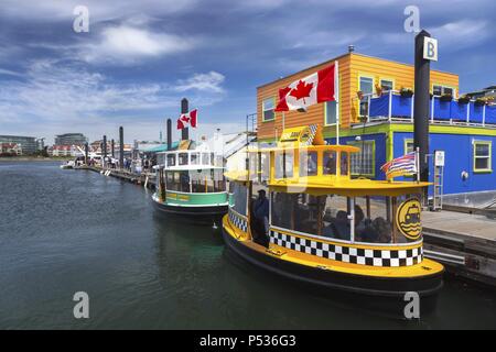 Turisti e acqua barche taxi in Fisherman Wharf vicino a Victoria City Center Porto Interno sull'Isola di Vancouver, British Columbia, Canada Foto Stock