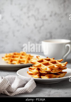 La prima colazione con cialde belghe e una tazza di caffè. di cemento grigio Sfondo. spazio copia Foto Stock