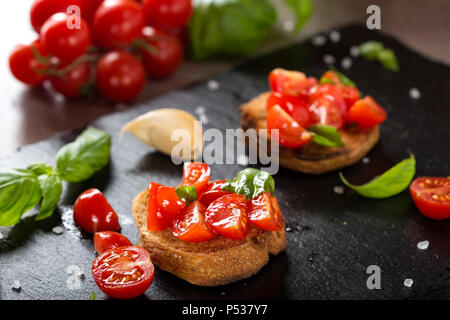 Antipasto Italiano chiamato Bruschetta condito con pomodoro, aglio e basilico - Vista ravvicinata Foto Stock