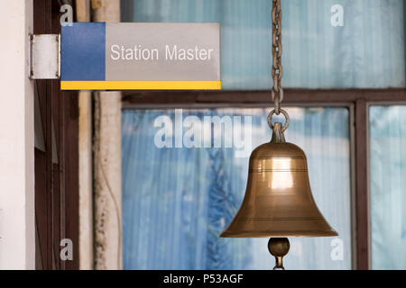 Closeup firmare la stazione master con un campanello d'oro in una stazione ferroviaria. Suono tradizionale segnalazione su piattaforma presso la stazione ferroviaria. Foto Stock