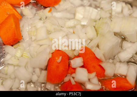 Le cipolle e le carote sono cotte in una padella. Foto Stock