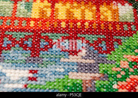 Cross-stitch. La fotografia macro di siti di ricamo. Tiro con un piccolo promontorio di nitidezza. Motivi luminosi sulla tela. Foto Stock