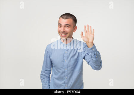 L'uomo con la maglietta blu dicendo ciao, agitando a mano. Benvenuti home iscriviti Foto Stock