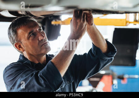 Autofficine riparazione di un sollevato auto in garage. Riparazione auto di uomini che fissa un auto in una stazione di servizio. Foto Stock