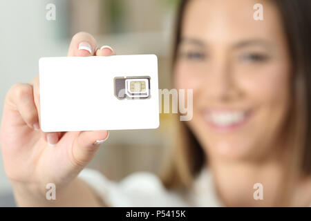 In prossimità di una donna felice mano che tiene una telefonia nuova scheda sim a casa Foto Stock