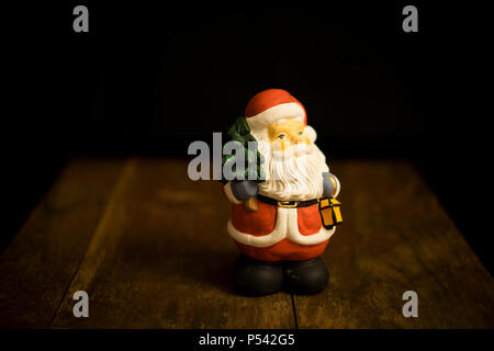 Babbo Natale in piedi sul tavolo di legno, bella e graziosa decorazione di Natale. Divertimento e happy photo. Foto Stock