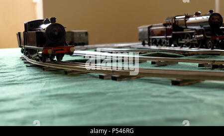 Primo piano vintage modello treno elettrico formato da una locomotiva a vapore e un verde le autovetture in esecuzione su rotaie Foto Stock