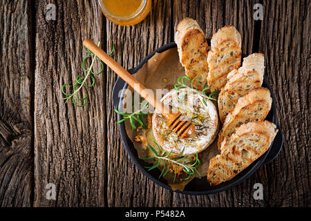 Cotta formaggio Camembert con rosmarino e miele. Il cibo gustoso. Vista dall'alto. Lay piatto Foto Stock