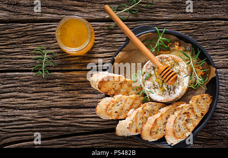 Cotta formaggio Camembert con rosmarino e miele. Il cibo gustoso. Vista dall'alto. Lay piatto Foto Stock