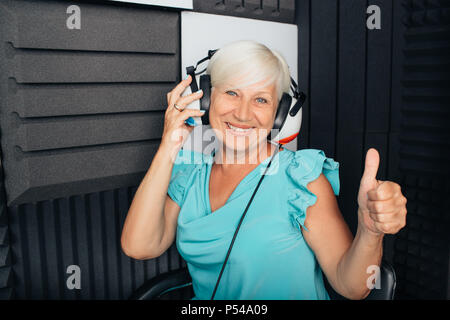 Donna anziana paziente durante l'esame dell'udito in una speciale sala audio Foto Stock