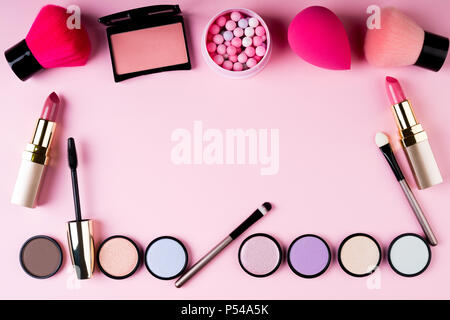 Telaio di prodotti da trucco e cosmetica decorativa su sfondo rosa laici piana. Moda e bellezza il concetto di blogging. Vista superiore, spazio di copia Foto Stock