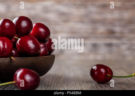 Fresche ciliege mature in un rustico ciotola di legno Foto Stock